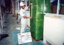 ヘルメット姿の作業員が柱の補強作業をしている写真