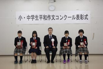 中学生の部受章者4名が盾を持って椅子に座っており、市長と並んで写っている写真