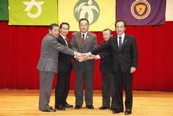 大崎市、色麻町、加美町、涌谷町、美里町の関係者の男性が手を伸ばして重ね合わせ、全員で握手をしている写真