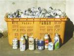 黄色いボックスコンテナの中にたくさんのアルミ缶が入っており、かごの前に色々な飲み物のアルミ缶が置かれている写真