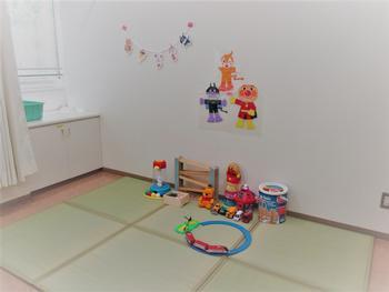 畳の上に子ども達のおもちゃや、壁にアンパンマンの絵などが飾られた支援センター内の写真