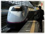 東北新幹線とホームに立つ乗客の写真