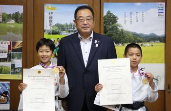 空手の道着を着て、金メダルと賞状を手にしている笑顔の笹原さん（右）と柴田さん（左）と大崎市長（中央）が並んでいる写真