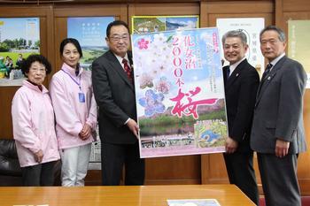 化女沼2000本桜の会から贈呈されたポスターを持っている市長と桜の会の代表者、桜の会のメンバーの写真