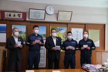 紺色の作業着を着た、ジャパンカーレスキュー株式会社の方4人と市長が各自マスクを持って記念写真