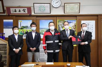 雨合羽を着た市長と株式会社JALエンジニアリングの方4人で記念写真