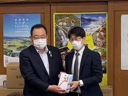 スーツを着た株式会社RSテクノロジーズ三本木工場の方と市長が並びマスクの箱を持ち記念写真