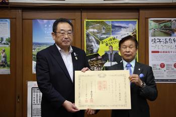 ジー・オー・ピー株式会社の代表の男性と市長が賞状を持って並んで立っている写真