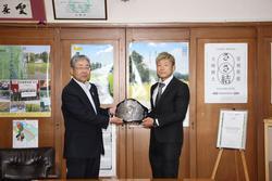 高橋副市長（左）とISAO選手（右）がチャンピオンベルトを持っている写真