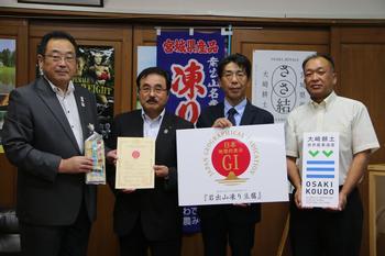 大崎市長（右端）、鈴木組合長（左から三人目）、鈴木（左から二人目）組合長・小松（左から三人目）組合長が凍り豆腐や登録証、GIマーク等を持って並んで写っている写真