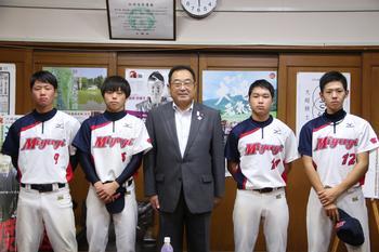 古川高等学校ソフトボール部員の表敬の際に撮影された4人のユニフォーム姿の部員と市長の記念写真