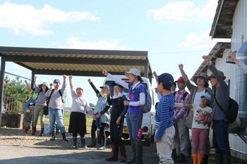 ささ結（ささむすび）の稲刈りの参加者がガッツポースをして掛け声をかけている写真