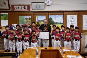 ユニフォームを着た大崎ジュニアドラゴンのメンバーと高橋副市長が笑顔でガッツポースをしている集合写真