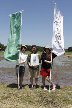 緑色と白色ののぼり旗を持って3人の石垣アナ、奥口アナ、名護アナが並んで写っている写真