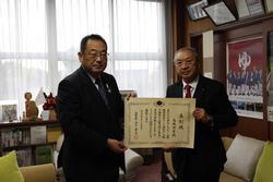 法務大臣表彰を受賞された古川人権擁護委員協議会会長の高橋興業氏（右）と市長が賞状を手に持って並んで写っている