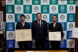 表彰を受けた千葉卓也代表取締役、渋谷誠司代表取締役が額に入った賞状を持って市長と並んで写っている写真