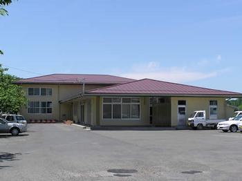 紫色の屋根の長岡地区公民館の建物と入り口付近の広々とした駐車場の写真