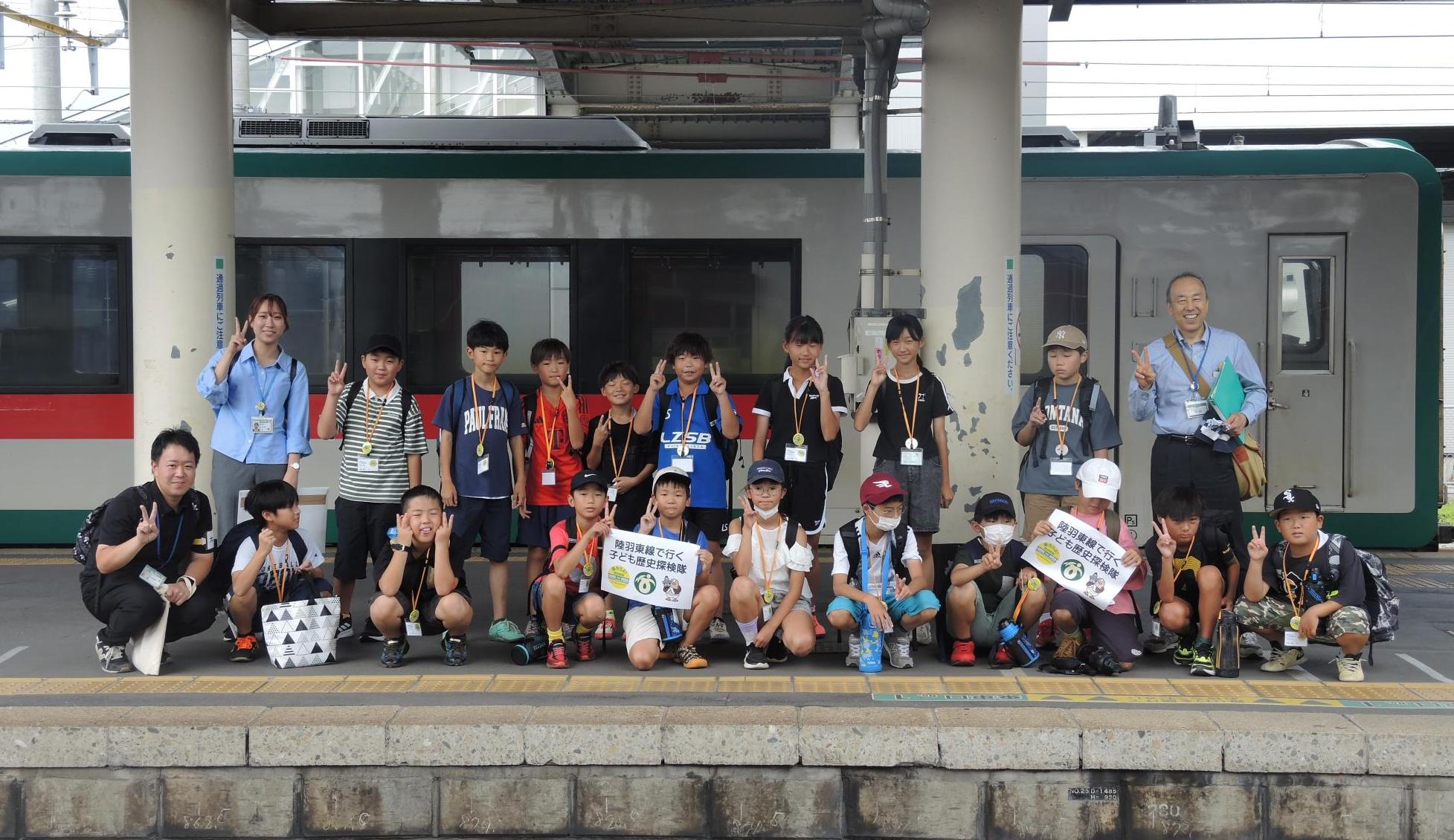 JR小牛田駅で、陸羽東線の列車を背景に、参加者で集合写真を撮りました