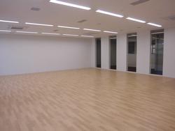 白い壁とフローリングの床の広々とした研修室内の写真
