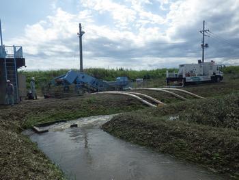 湛水部分に4本のホースを伸ばして川に配水している排水作業の様子の写真